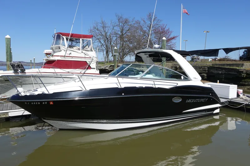 Slide: The Image of 2018 Monterey 295 Sport Yacht docked in a marina, featuring sleek black and white design. - 0