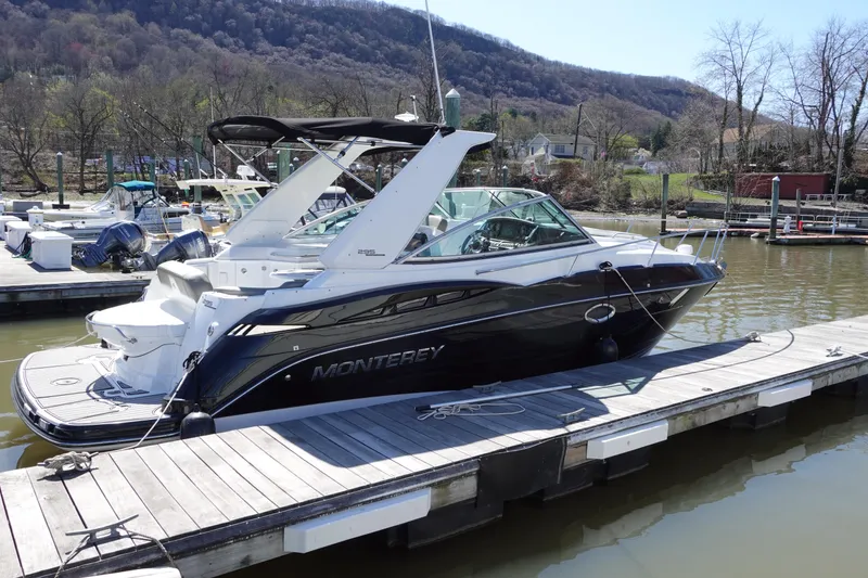 Slide: The Image of 2018 Monterey 295 Sport Yacht docked on a serene lake with scenic mountain backdrop. - 1