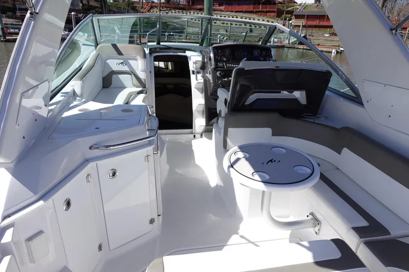 Slide: The Image of 2018 Monterey 295 Sport Yacht interior with seating, table, and helm, docked at marina. - 14