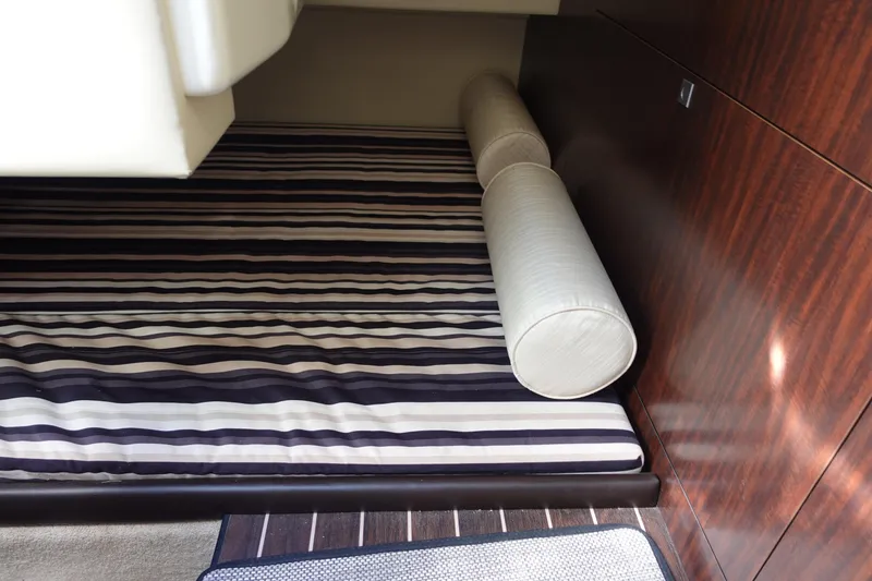 Slide: The Image of 2018 Monterey 295 Sport Yacht interior with striped bedding and wooden paneling. - 24