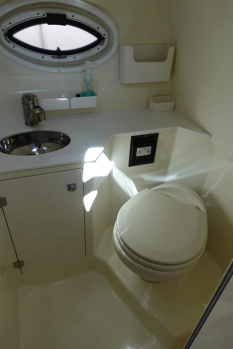 Slide: The Image of 2018 Monterey 295 Sport Yacht bathroom with sink, toilet, and porthole window. - 25