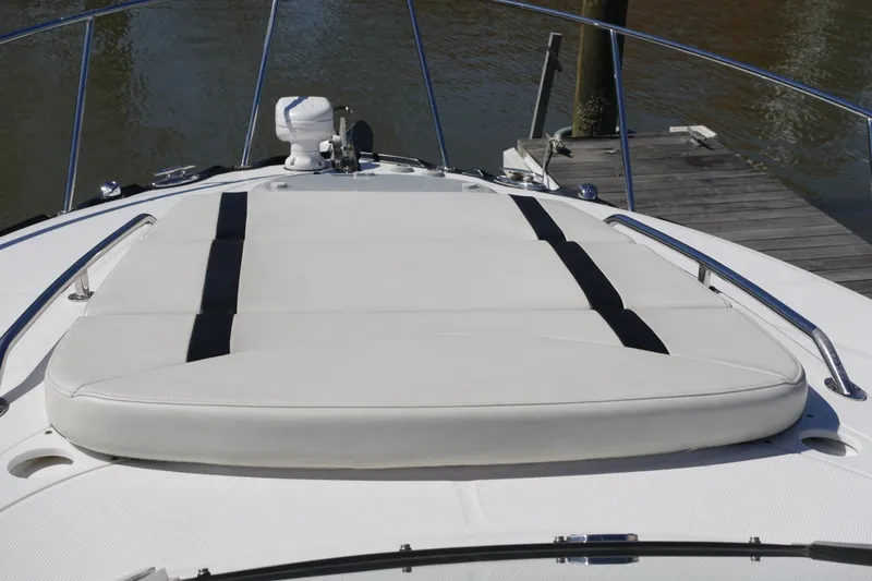Slide: The Image of 2018 Monterey 295 Sport Yacht bow with sun pad and railing, docked by water. - 4