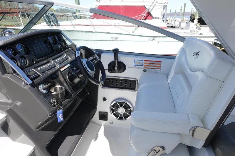 Slide: The Image of 2018 Monterey 295 Sport Yacht cockpit with steering wheel, controls, and white seating. - 9