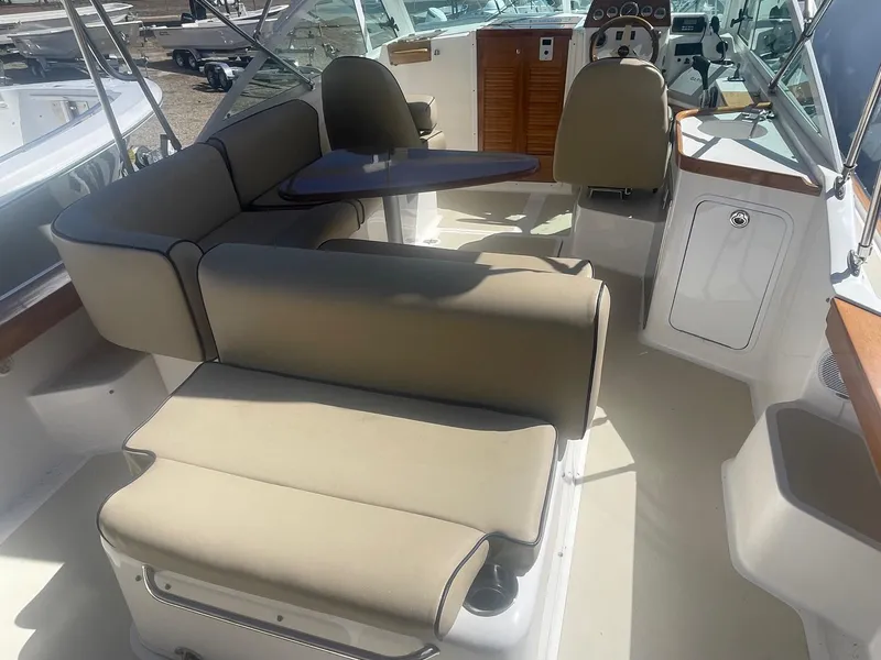 Slide: The Image of Interior of 2010 Hunt Yachts Harrier 25, featuring beige seating and a compact table. - 19