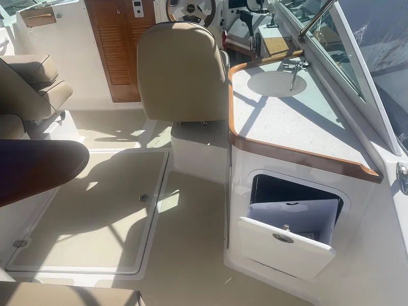 Slide: The Image of 2010 Hunt Yachts Harrier 25 interior with seating, steering wheel, and storage compartment. - 23