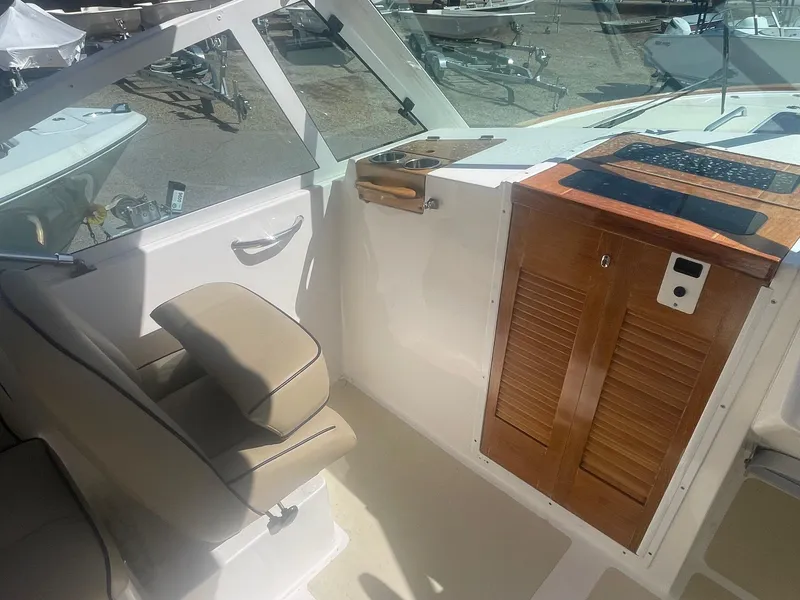 Slide: The Image of 2010 Hunt Yachts Harrier 25 interior with beige seating and wooden console. - 25