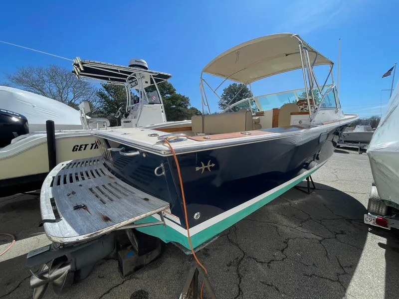 Slide: The Image of 2010 Hunt Yachts Harrier 25 boat with canopy, docked outdoors under clear blue sky. - 6