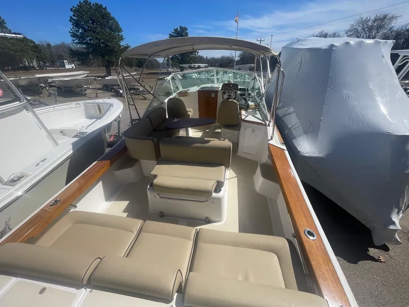 Slide: The Image of 2010 Hunt Yachts Harrier 25 with beige seating and canopy, docked outdoors. - 9