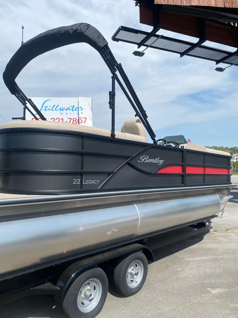 Slide: The Image of 2025 Bentley Pontoons Legacy 223 Navigator on trailer, black and red design. - 16
