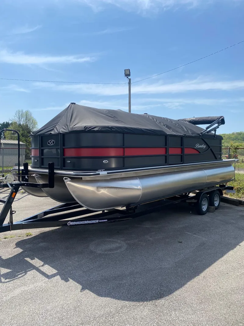 Slide: The Image of 2025 Bentley Pontoons Legacy 223 Navigator on trailer, covered, parked outdoors. - 2