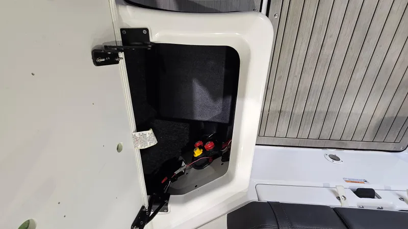 Slide: The Image of 2021 Yamaha Boats 212SD storage compartment with open hatch, showcasing interior details and wiring. - 28