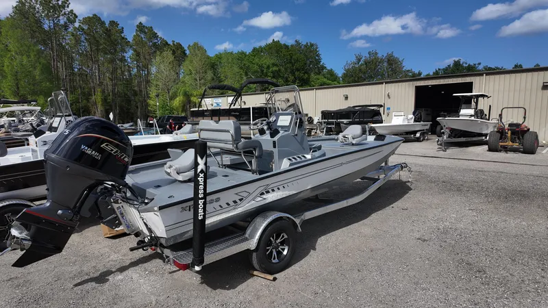 Slide: The Image of 2025 Xpress H20B boat on trailer, parked outdoors near a warehouse. - 13