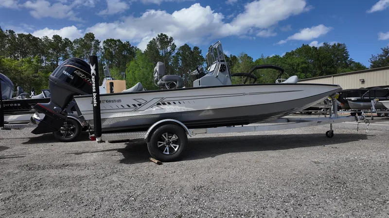 Slide: The Image of 2025 Xpress H20B boat on trailer, parked outdoors under a partly cloudy sky. - 2