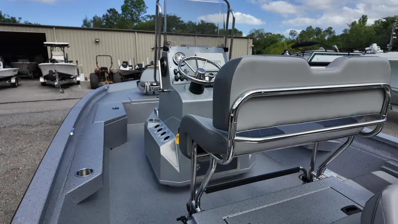 Slide: The Image of 2025 Xpress H20B boat interior with steering console and seating, parked near a warehouse. - 27
