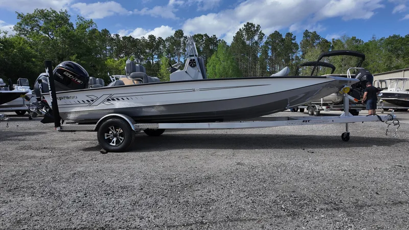 Slide: The Image of 2025 Xpress H20B boat on trailer, parked outdoors with trees in background. - 7