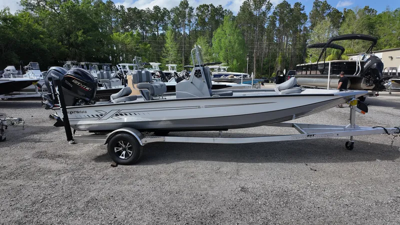Slide: The Image of 2025 Xpress H20B boat on trailer, parked outdoors with other boats in the background. - 8