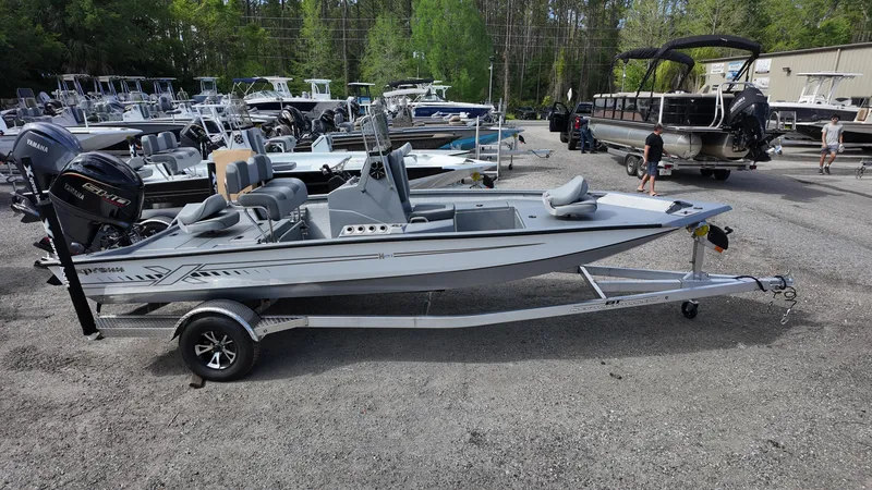 Slide: The Image of 2025 Xpress H20B boat on trailer in a marina with other boats. - 9