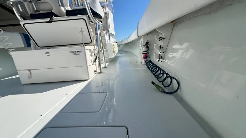 Slide: The Image of 2005 Contender 36 boat deck with seating and coiled hose, under clear blue sky. - 16