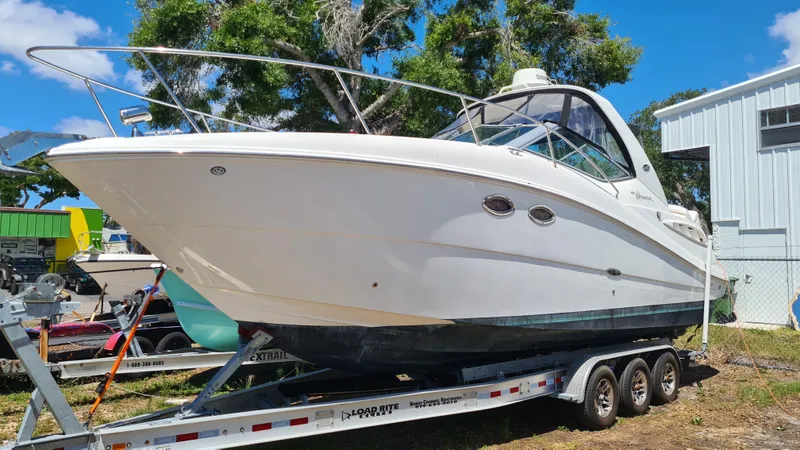 The Image of 2007 Sea Ray 290 Sundancer boat on trailer, parked outdoors under clear sky. - 0