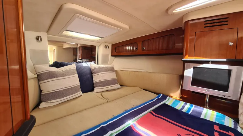 Slide: The Image of 2007 Sea Ray 290 Sundancer cabin interior with cozy bedding and compact TV. - 12