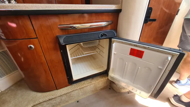 Slide: The Image of Open mini fridge inside 2007 Sea Ray 290 Sundancer boat cabin, showcasing interior shelving. - 15