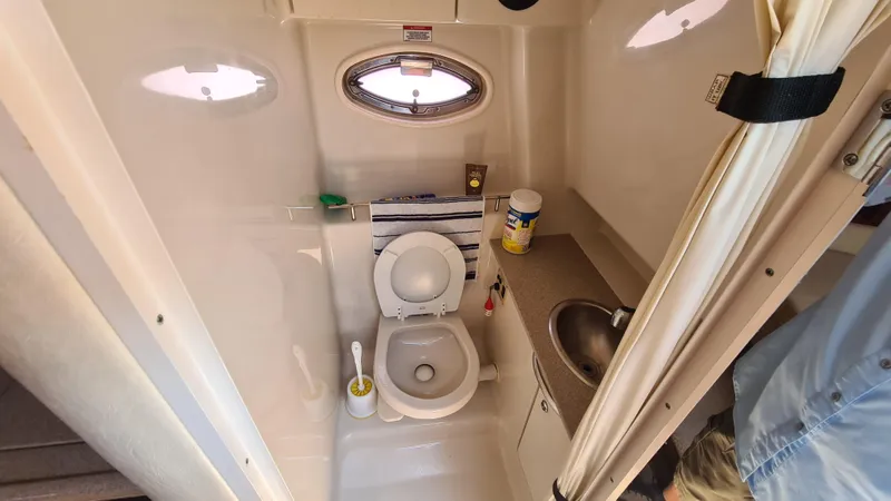 Slide: The Image of 2007 Sea Ray 290 Sundancer bathroom with toilet, sink, and porthole window. - 16