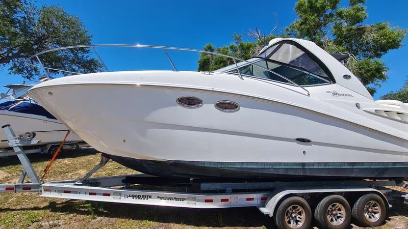 Slide: The Image of 2007 Sea Ray 290 Sundancer boat on trailer, parked outdoors under clear blue sky. - 2