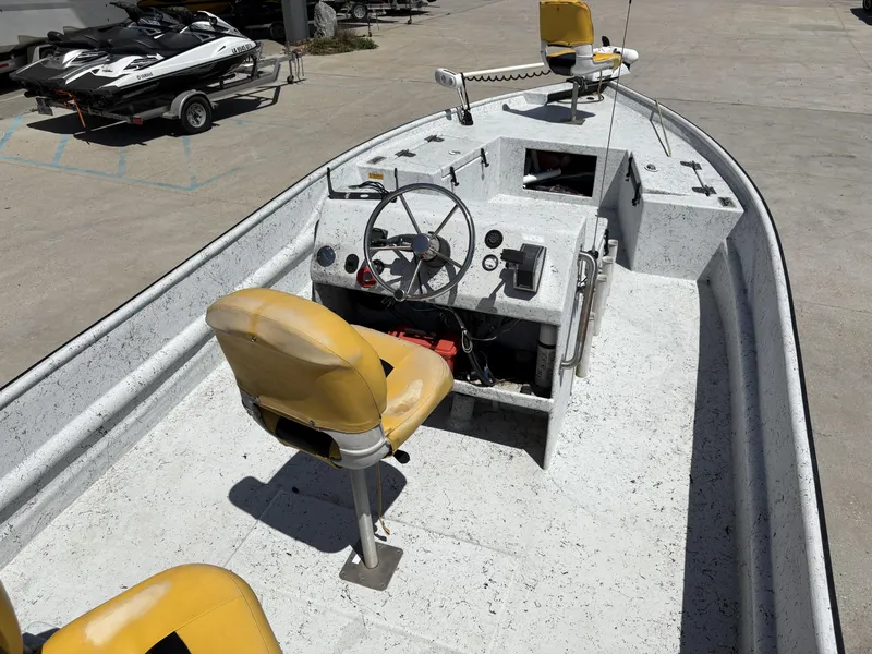 Slide: The Image of 2011 Skiff Reno 22 boat with yellow seats and steering console, parked on concrete. - 4
