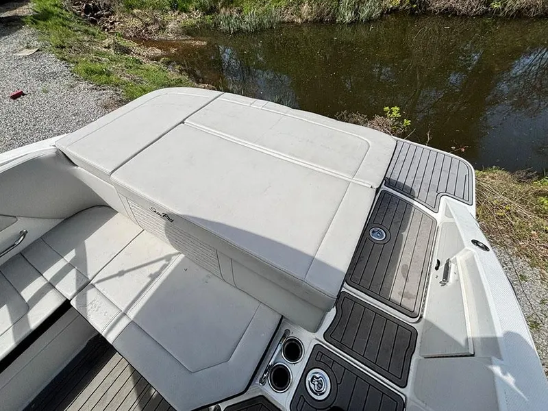 Slide: The Image of 2022 Sea Ray SPX 230 boat interior with cushioned seating and sleek design by a waterway. - 5