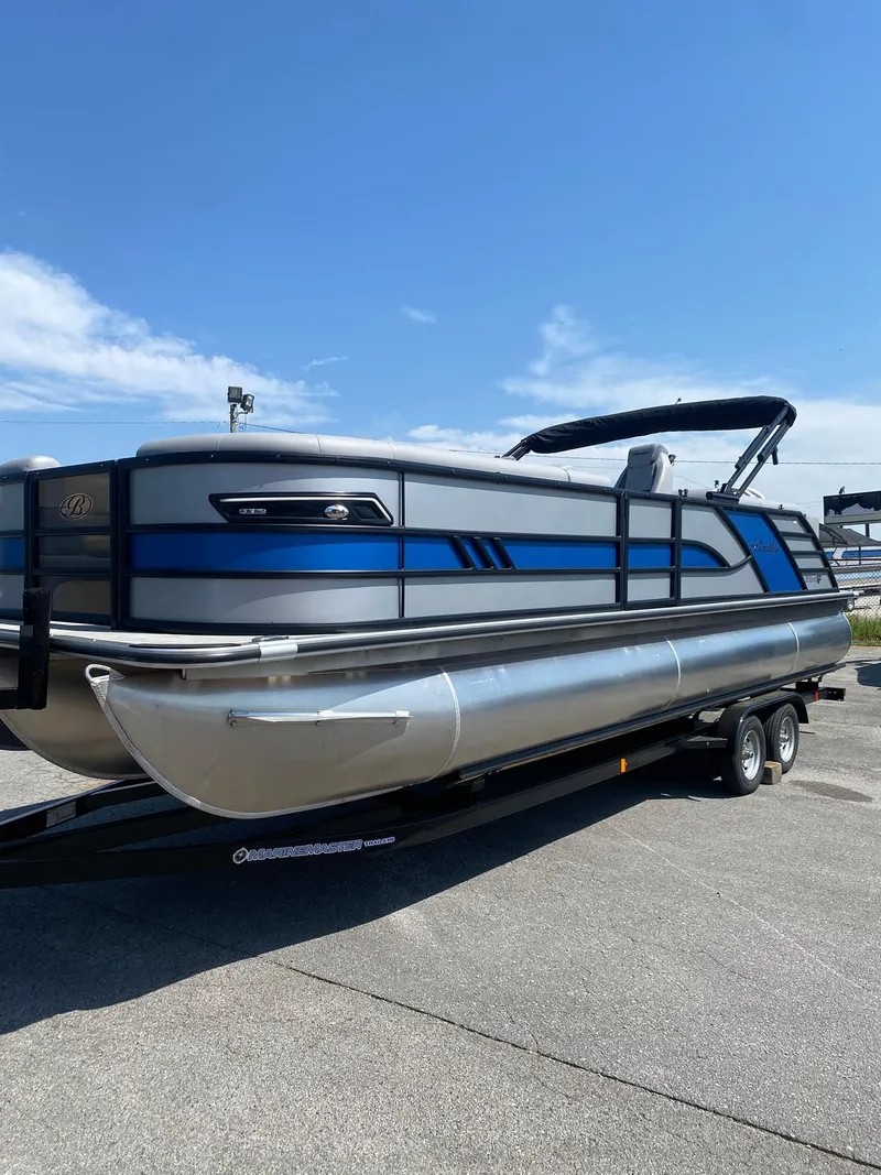 Slide: The Image of 2025 Bentley Pontoons Elite 253 Admiral on trailer, sleek design, blue accents, sunny day. - 10