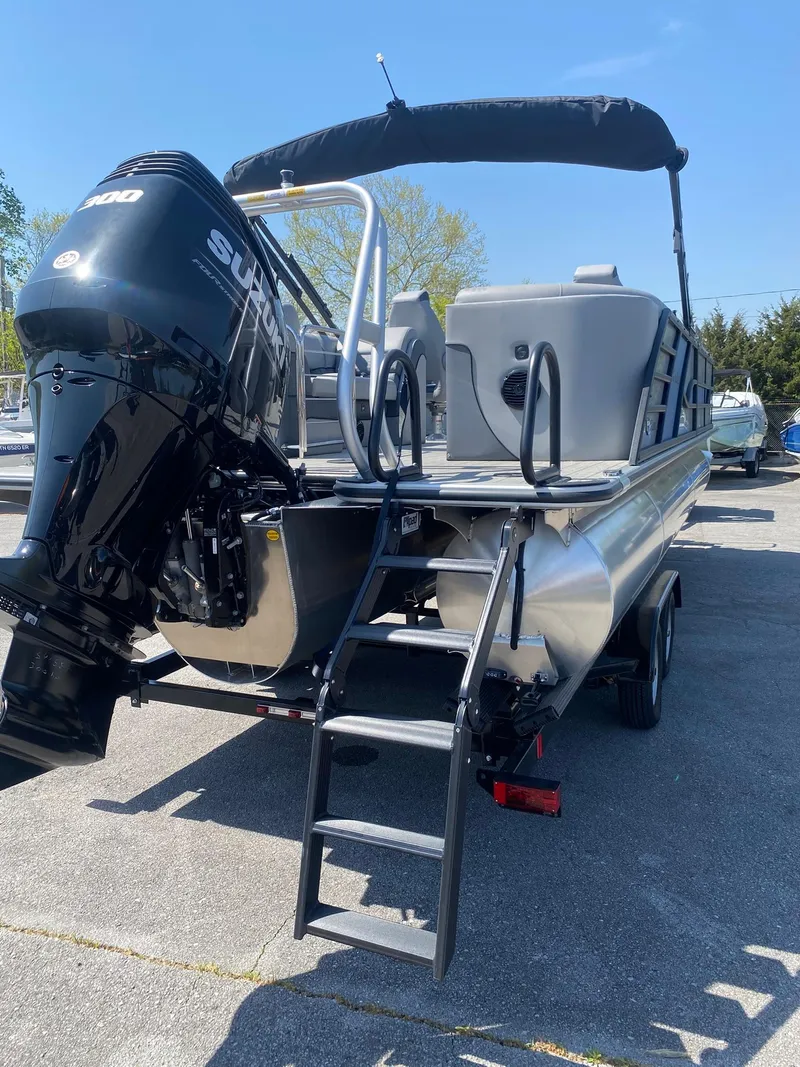 Slide: The Image of 2025 Bentley Pontoons Elite 253 Admiral with outboard motor and ladder, parked on pavement. - 18