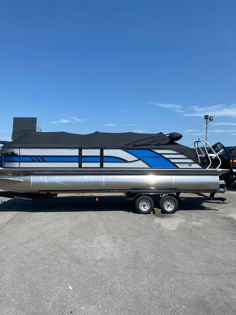 Slide: The Image of 2025 Bentley Pontoons Elite 253 Admiral pontoon boat on trailer under clear blue sky. - 37