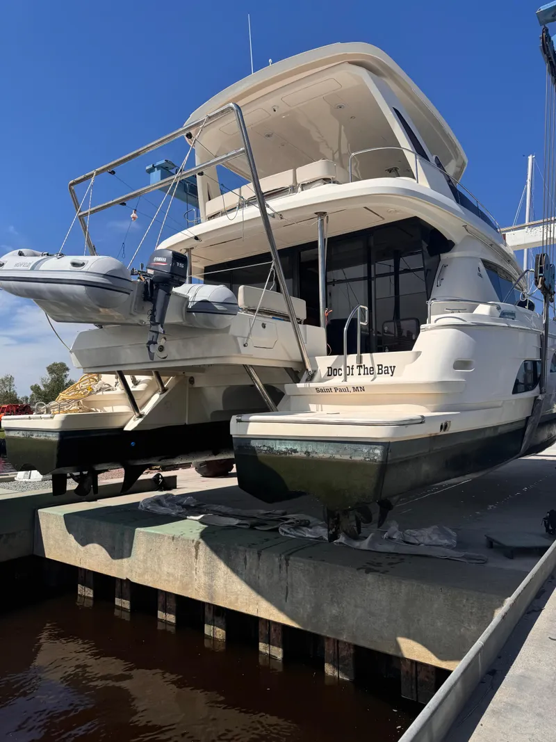 Slide: The Image of 2018 Aquila 48 yacht docked, featuring a small boat on the stern. - 12