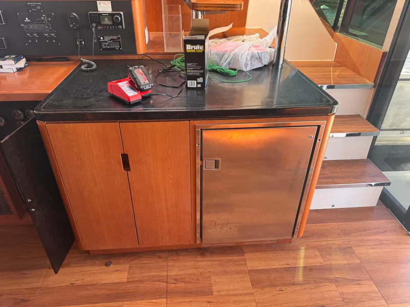Slide: The Image of Wooden cabinet with black countertop on Aquila 48 yacht, featuring a small fridge and electronic equipment. - 34