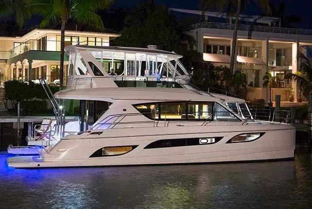 Slide: The Image of Luxurious 2018 Aquila 48 yacht illuminated at night, docked near waterfront homes. - 47