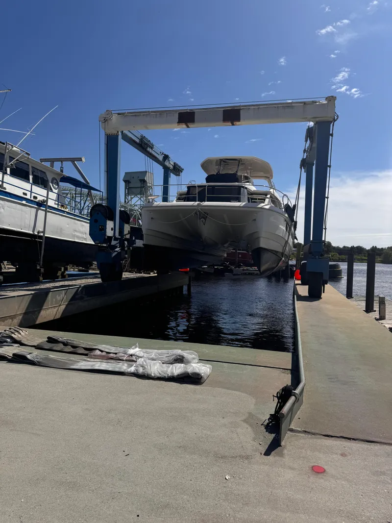 Slide: The Image of Aquila 48 yacht being lifted at a marina, clear blue sky above. - 9