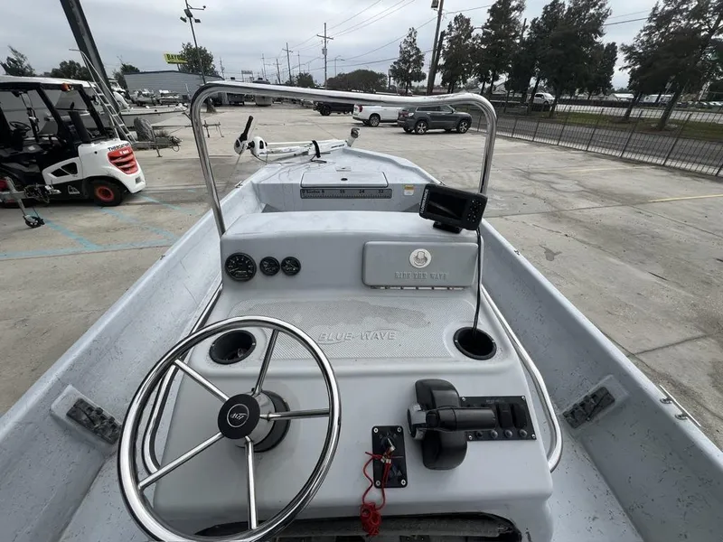 Slide: The Image of 2014 Blue Wave 2200 boat dashboard with steering wheel and controls in a parking lot. - 11