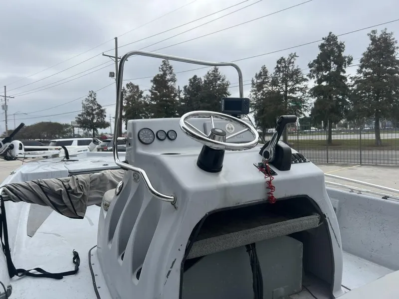Slide: The Image of 2014 Blue Wave 2200 boat console with steering wheel and controls, parked outdoors. - 13