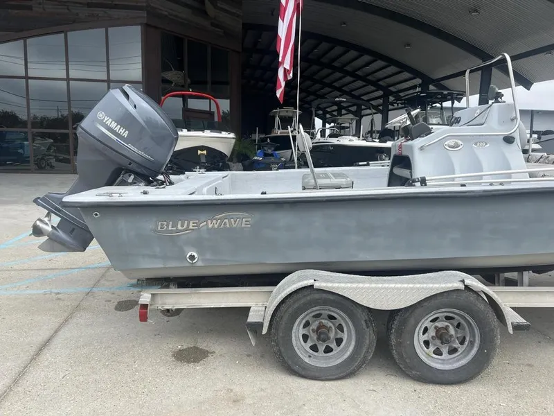 Slide: The Image of 2014 Blue Wave 2200 boat on trailer with Yamaha outboard motor, parked outside a showroom. - 6