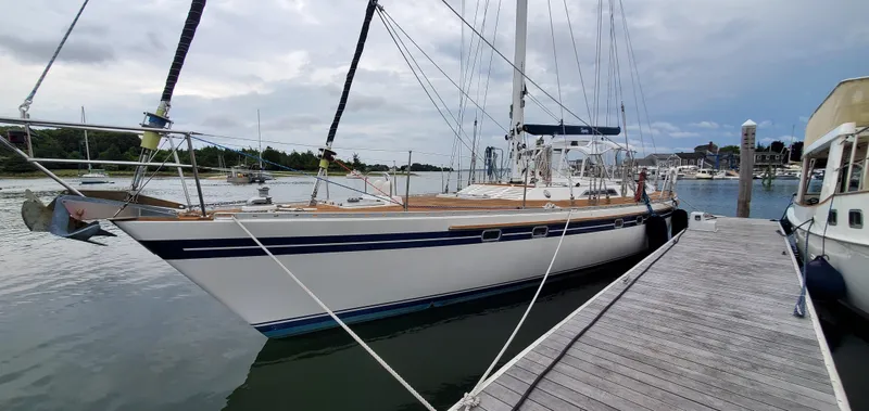 The Image of 1989 Tayana 55 sailboat docked at marina, overcast sky, calm waters. - 0
