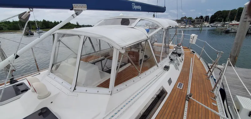 Slide: The Image of 1989 Tayana 55 sailboat with wooden deck, docked in a marina, featuring a covered cockpit. - 12