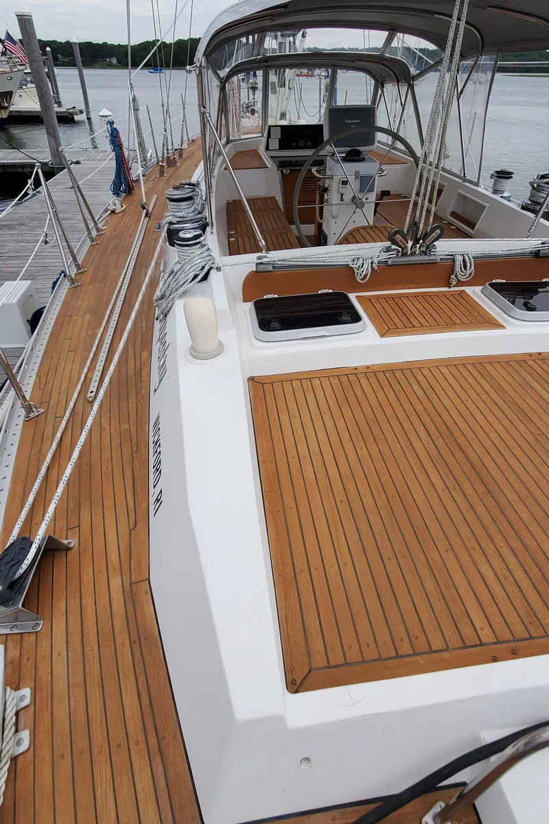 Slide: The Image of 1989 Tayana 55 sailboat with teak deck, docked at marina, featuring spacious cockpit and steering wheel. - 13