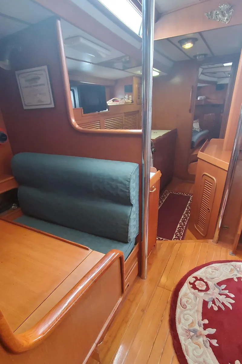 Slide: The Image of Interior of 1989 Tayana 55 yacht, featuring wooden furnishings and cozy seating area. - 23