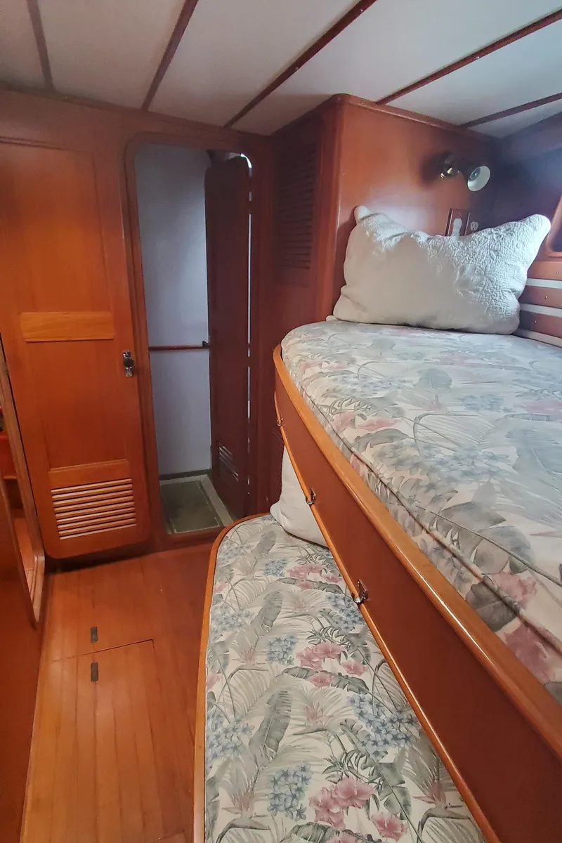 Slide: The Image of Interior of 1989 Tayana 55 yacht with wooden bunk beds and floral bedding. - 31