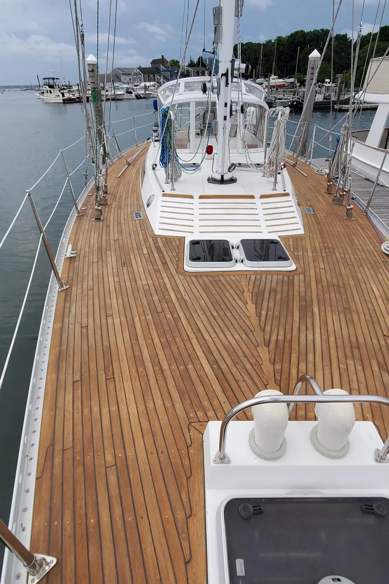 Slide: The Image of 1989 Tayana 55 sailboat with teak deck, docked at marina, showcasing elegant design and craftsmanship. - 36