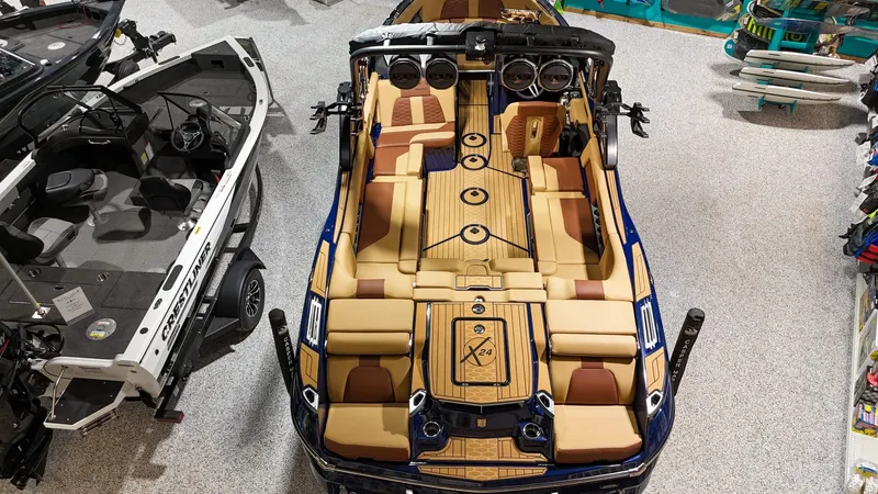 Slide: The Image of 2025 MasterCraft X24 boat with luxurious tan interior, displayed in a showroom. - 2