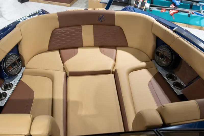 Slide: The Image of 2025 MasterCraft X24 boat interior with tan and brown seating, cup holders, and speakers. - 3