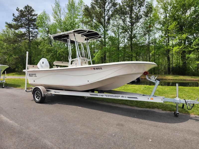 Slide: The Image of 2023 Carolina Skiff 21 LS boat on trailer, parked outdoors near trees. - 1