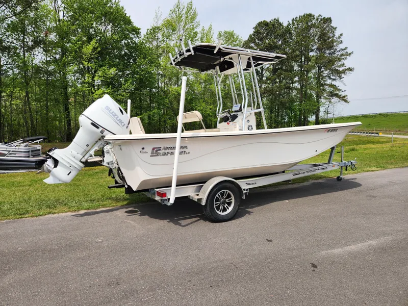 Slide: The Image of 2023 Carolina Skiff 21 LS boat on trailer, parked on road near trees. - 2
