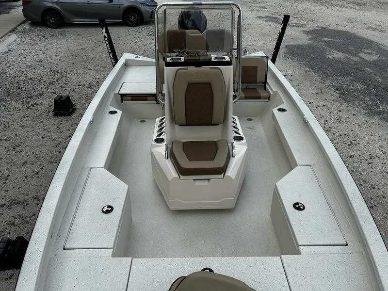 Slide: The Image of 2025 Xpress H20 BAY boat interior with seating and console, parked on gravel. - 6
